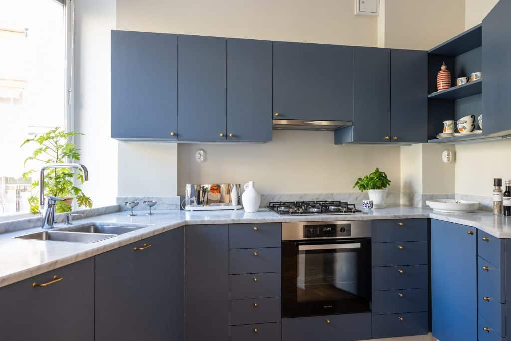 Tumši zila stūra virtuve ar skapīšu sistēmu