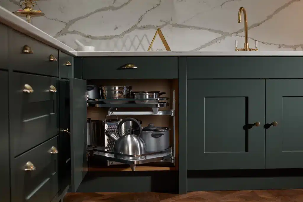 Virtuves stūrītis ar virtuves mehānismiem. Tumši zaļa virtuve ar zelta krāsas furnitūru.